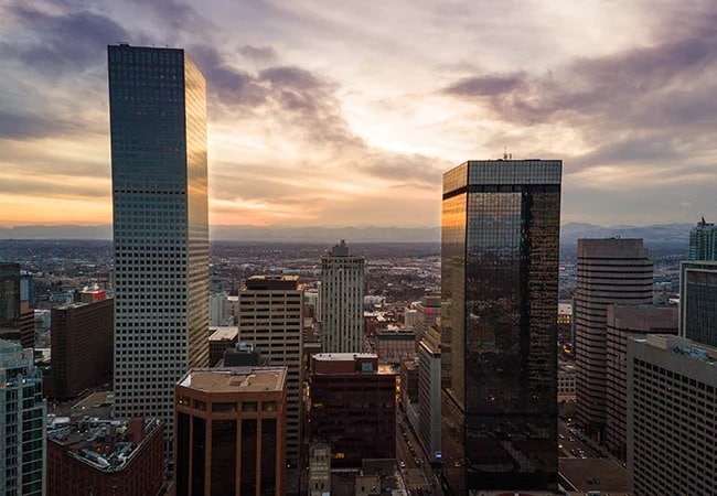 about-riverbend The sky displays a blend of warm and cool tones, with the sun casting a golden glow on the buildings.
