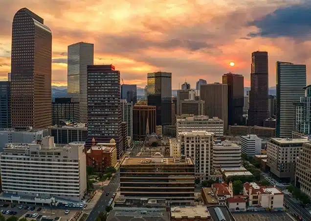 This image showcases a city skyline at sunset, with tall skyscrapers and modern buildings bathed in golden light. 