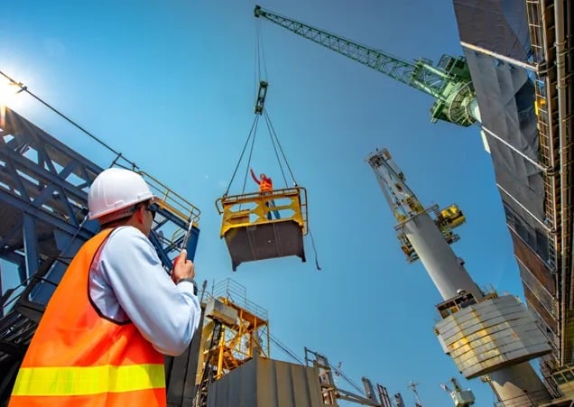 high-risk-construction-projects High-risk construction project with workers operating heavy machinery on a multi-level scaffolding structure, wearing safety gear such as helmets and harnesses.