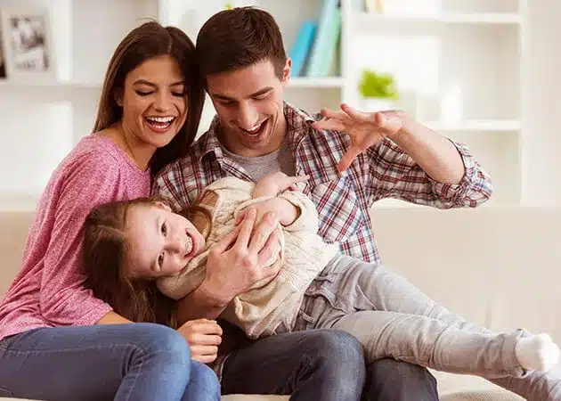 An elderly couple sitting together on a couch, smiling and enjoying a warm moment with their loved ones in a cozy home setting.