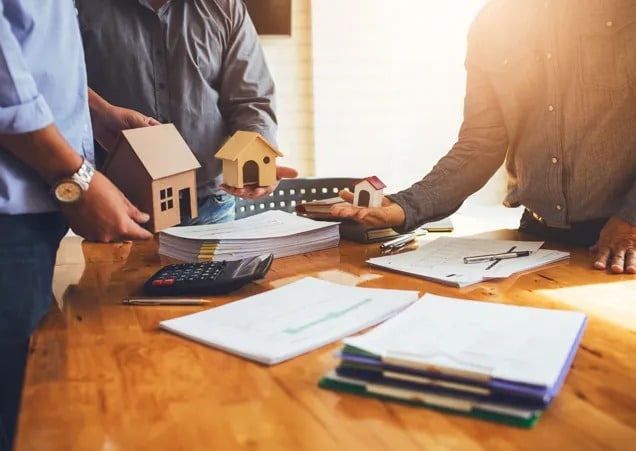 Construction business insurance offer – A handshake between two professionals with construction plans.